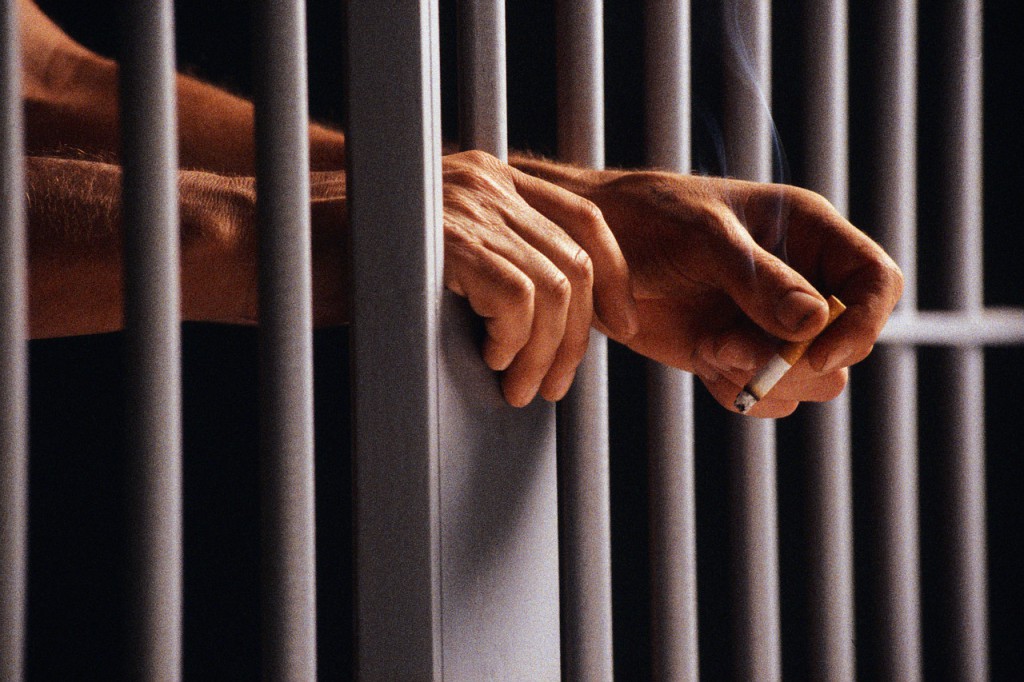 Prisoner Holding Cigarette Between Bars