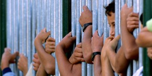 CHILDREN LOOK THROUGH A FENCE WAITING FOR BAHRAK IN KFAR MANDA