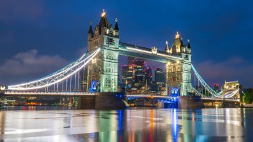 Tower Bridge de Londres se ilumina al anochecer, reflejando sus brillantes luces sobre las tranquilas aguas del río Támesis. Esta imagen captura la arquitectura victoriana en contraste con el horizonte moderno [&hellip;]