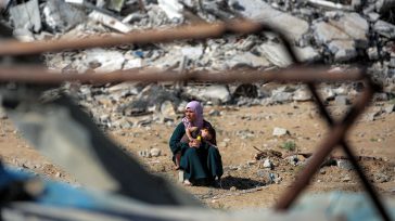 Una madre abraza a su hijo en medio de escombros masivos que testifican el genocidio,  la destrucción total de su entorno y la pérdida de sus hogares, reflejando la devastación […]