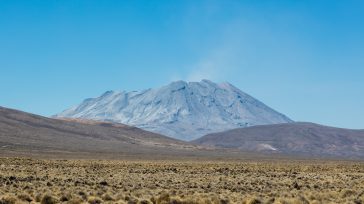 El imponente Volcán Ubinas, el más activo de Perú, se alza majestuoso con su cumbre cubierta de ceniza, dominando un árido y extenso paisaje andino.    