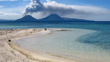 Una paradisíaca playa de arenas claras y aguas cristalinas contrasta con la imponente fuerza de la naturaleza al fondo. Allí, un volcán en plena erupción alza una densa y oscura [&hellip;]